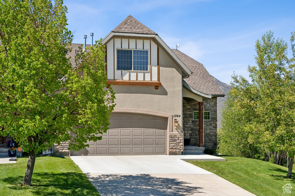 Tudor home with a garage and a front lawn