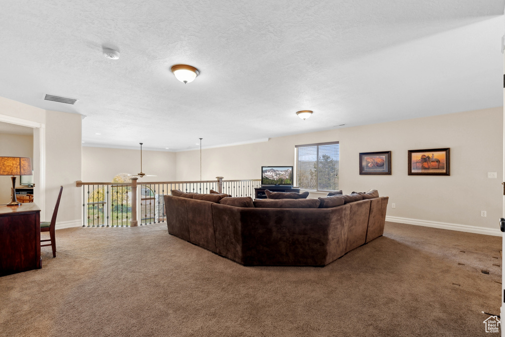 Living room featuring a textured ceiling, ceiling fan, and carpet floors