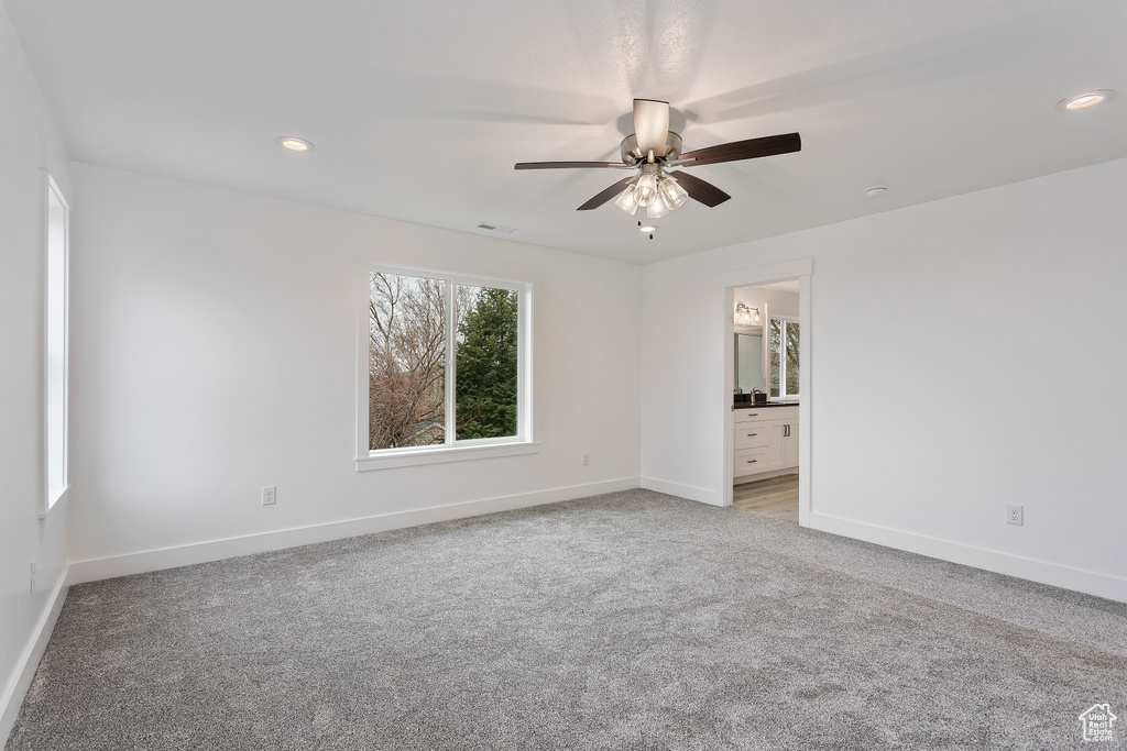 Unfurnished bedroom with light carpet, connected bathroom, and ceiling fan