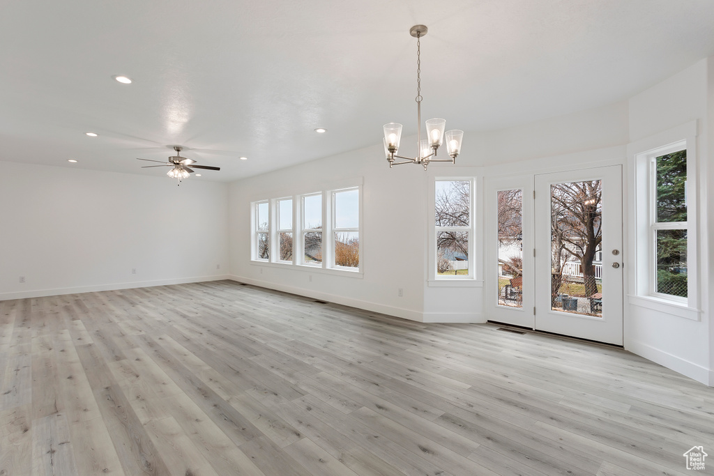 Unfurnished dining area with light hardwood / wood-style flooring and ceiling fan with notable chandelier