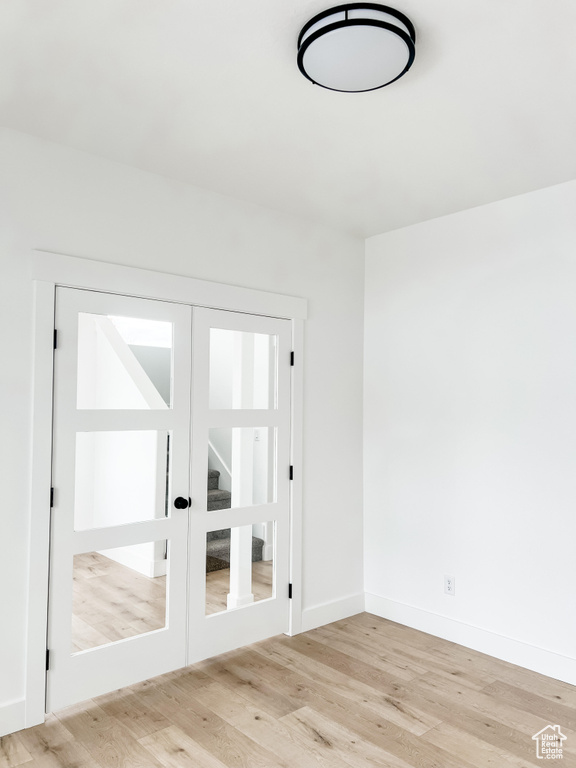 Unfurnished room featuring french doors and light wood-type flooring