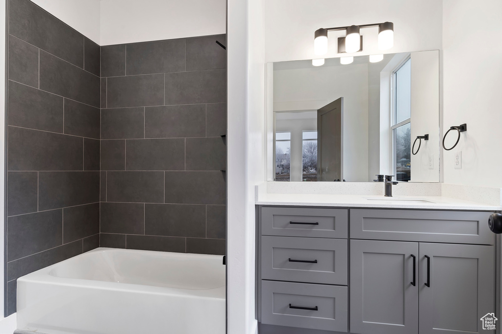 Bathroom with tiled shower / bath combo and vanity