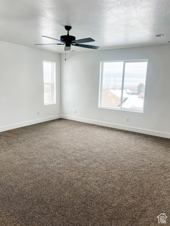 Empty room featuring ceiling fan, a textured ceiling, and carpet flooring