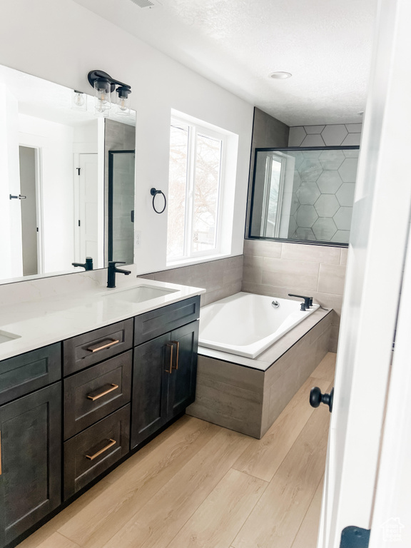 Bathroom with dual bowl vanity, tiled tub, and hardwood / wood-style flooring