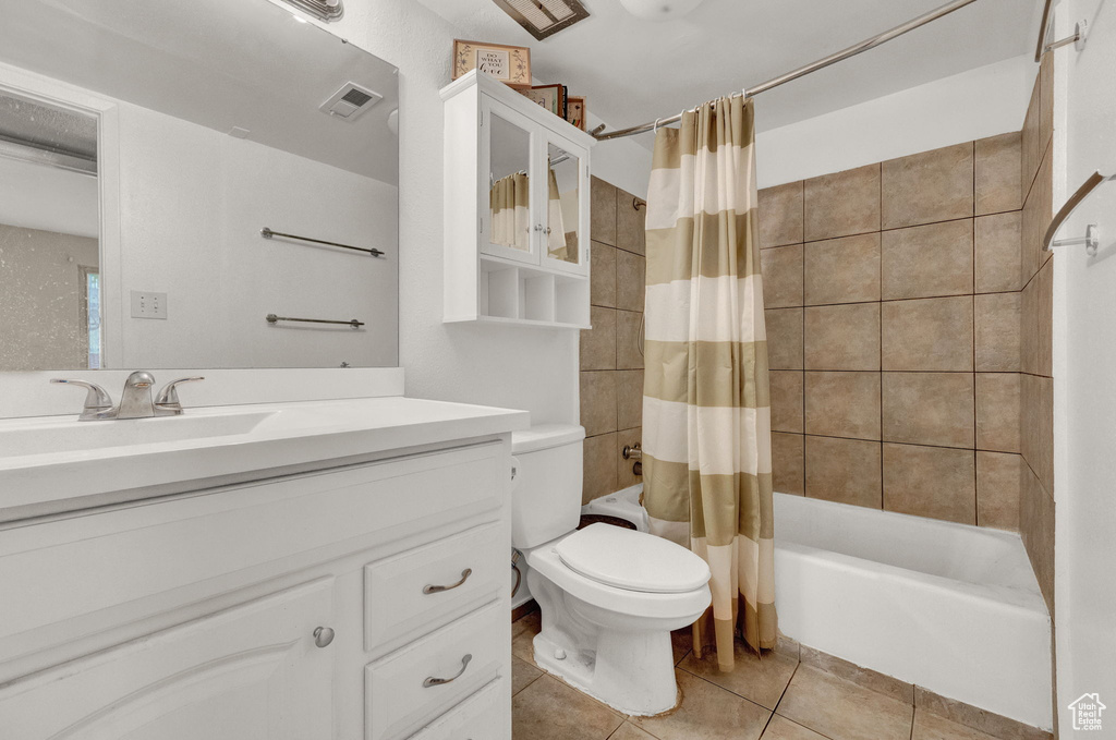 Full bathroom with tile floors, shower / bath combo, toilet, and vanity