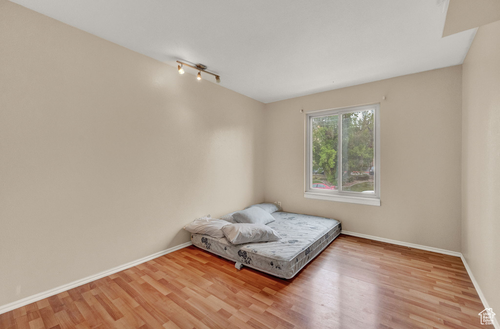 Unfurnished room with track lighting and light wood-type flooring