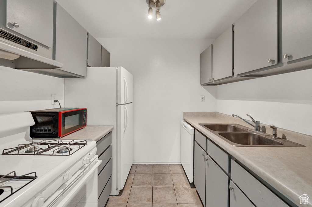 Kitchen with gray cabinetry, sink, white appliances, and light tile floors