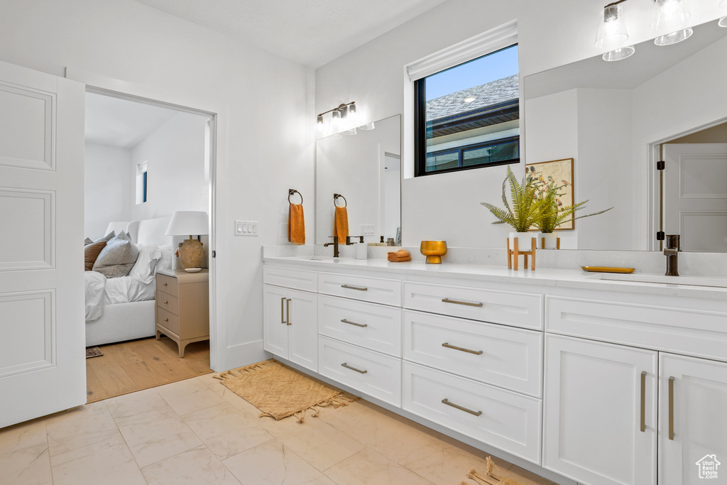 Bathroom featuring dual sinks, vanity with extensive cabinet space, and hardwood / wood-style floors