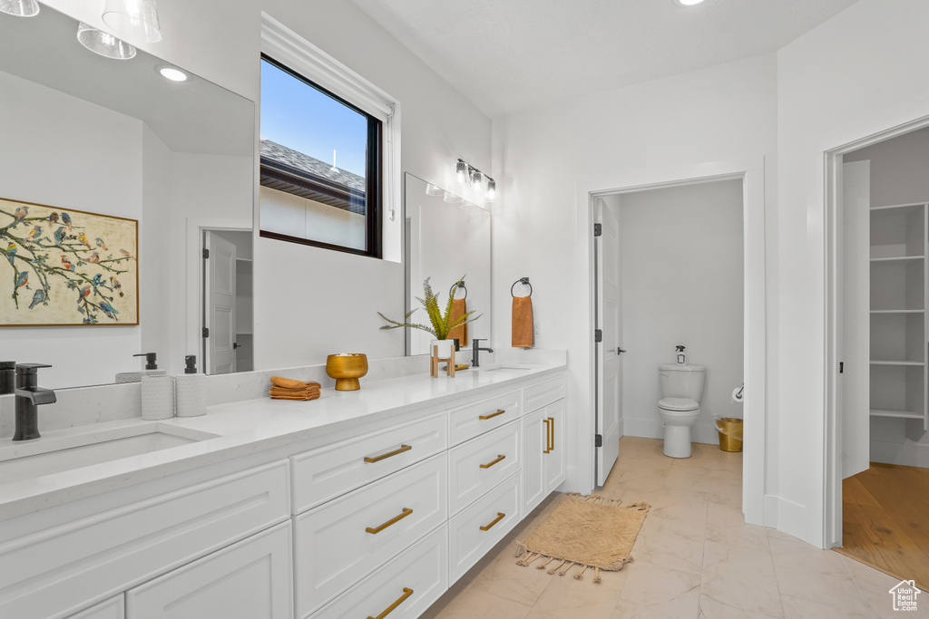 Bathroom featuring double vanity, toilet, and tile floors