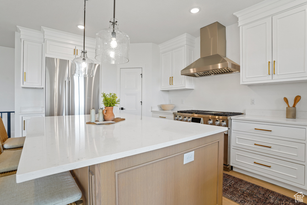 Kitchen featuring wall chimney exhaust hood, a kitchen island, gas range oven, and dark wood-type flooring