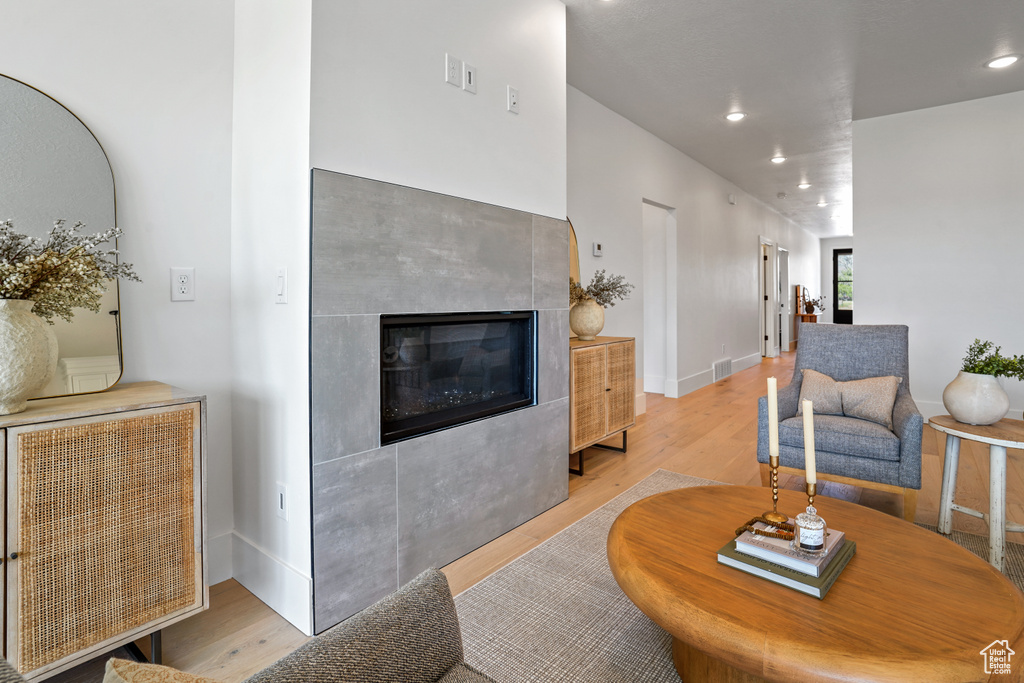 Living room with a tile fireplace and light wood-type flooring