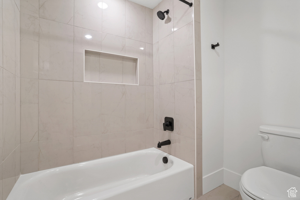 Bathroom with toilet and tiled shower / bath combo