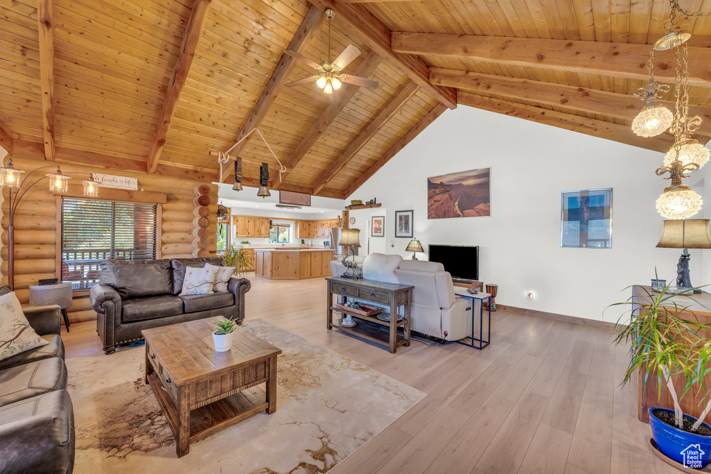 Living room with beam ceiling, wood-type flooring, rustic walls, wood ceiling, and ceiling fan