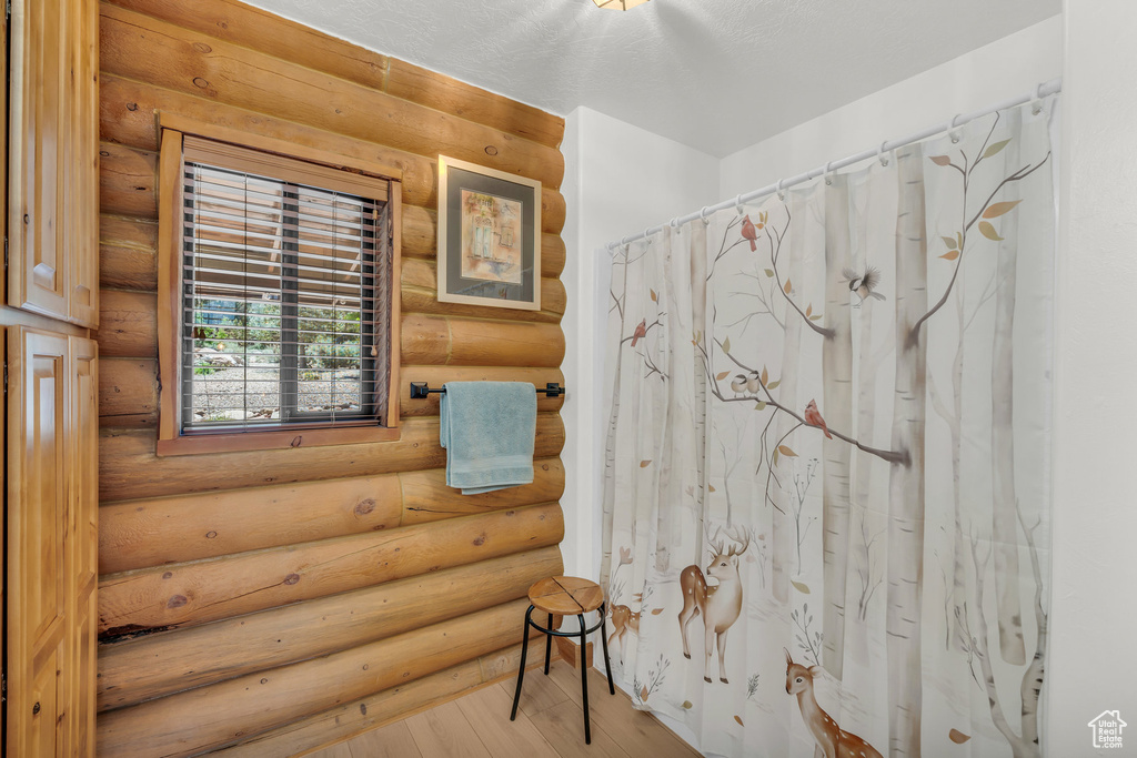 Bathroom with rustic walls and hardwood / wood-style floors