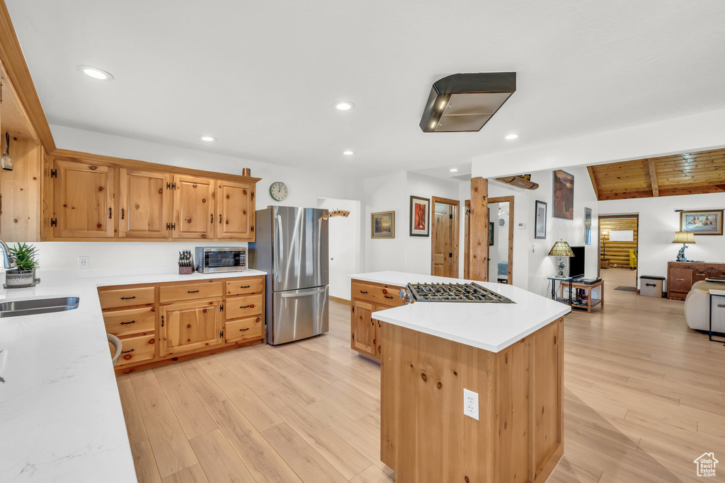Kitchen featuring light hardwood / wood-style floors, lofted ceiling with beams, a kitchen island, appliances with stainless steel finishes, and sink