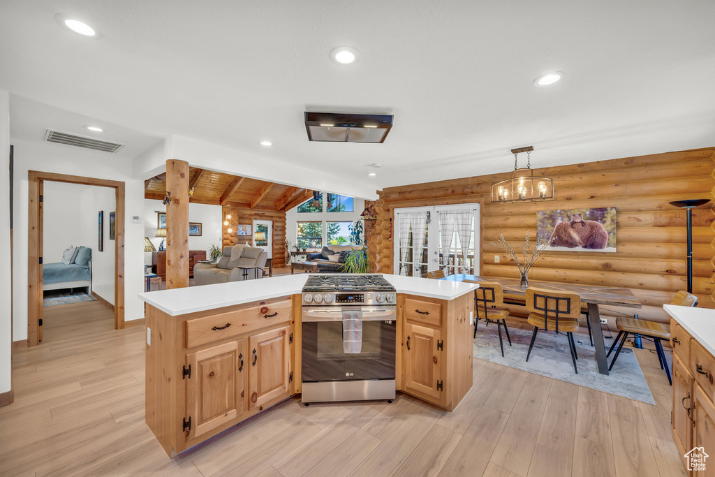 Kitchen with lofted ceiling with beams, stainless steel gas range, light hardwood / wood-style flooring, log walls, and light brown cabinets