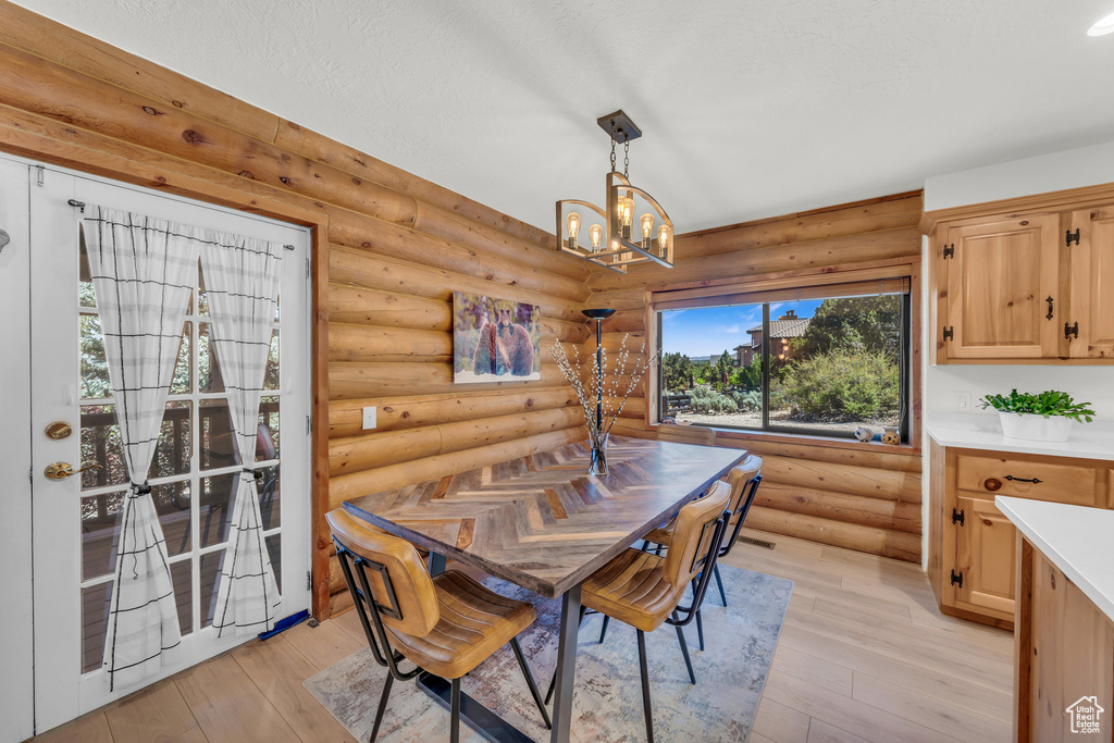 Dining area featuring light hardwood / wood-style flooring, log walls, and a chandelier