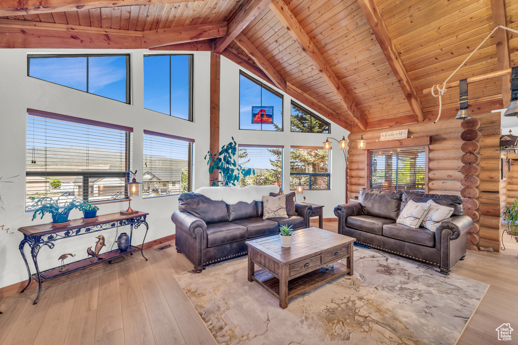 Living room featuring high vaulted ceiling, wooden ceiling, log walls, and hardwood / wood-style floors