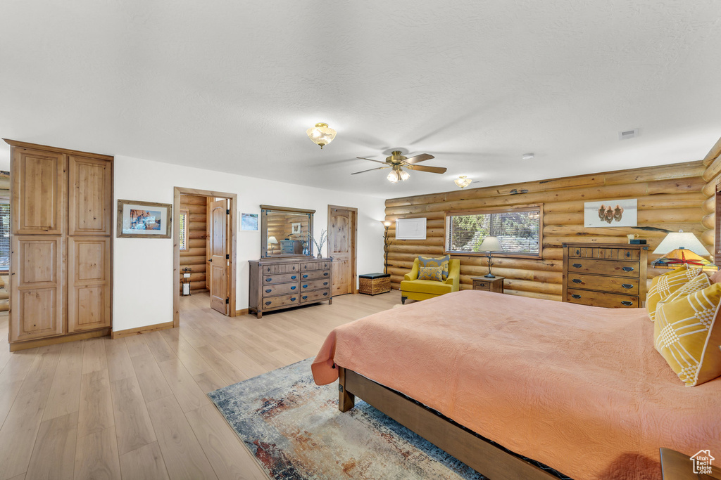 Bedroom featuring ceiling fan, light hardwood / wood-style floors, and log walls