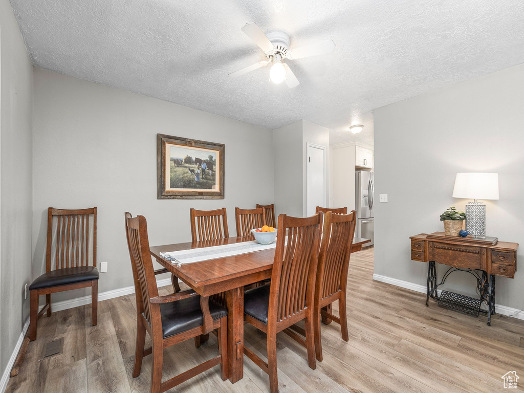 Dining area featuring ceiling fan, light hardwood / wood-style floors, and a textured ceiling