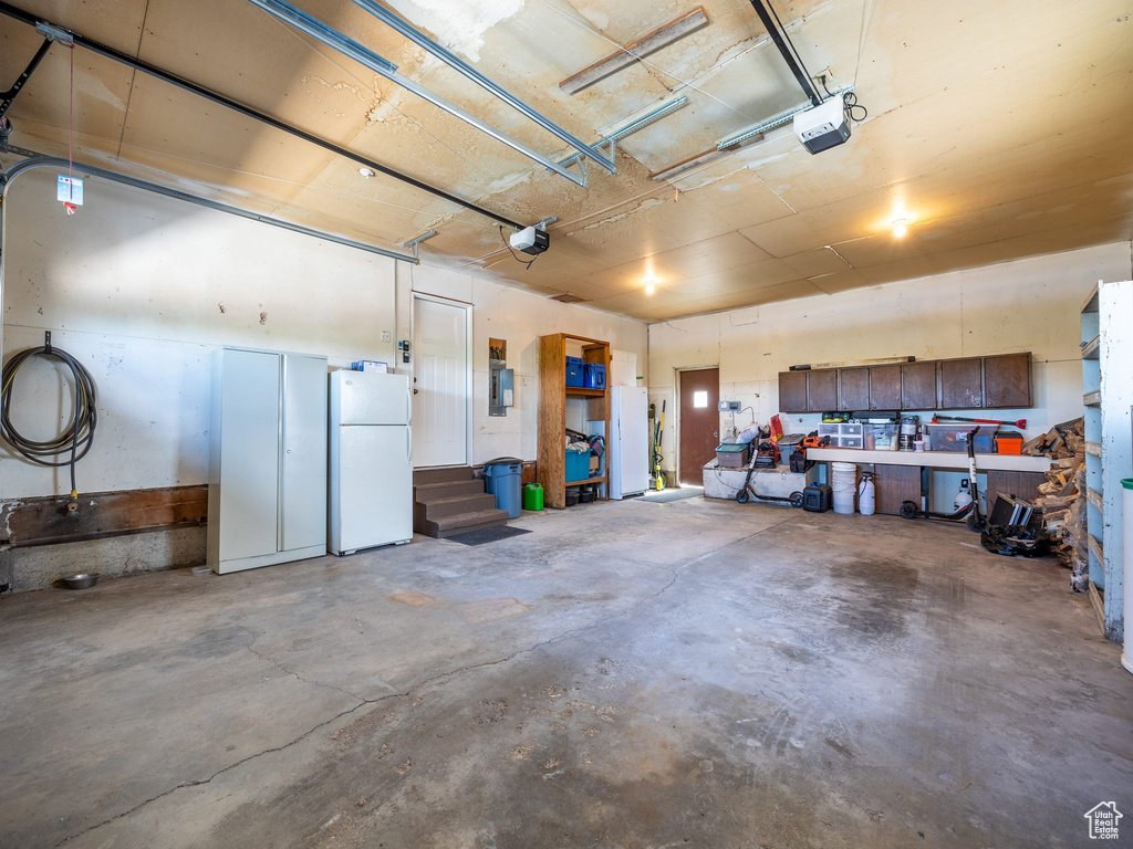 Garage featuring white refrigerator and a garage door opener