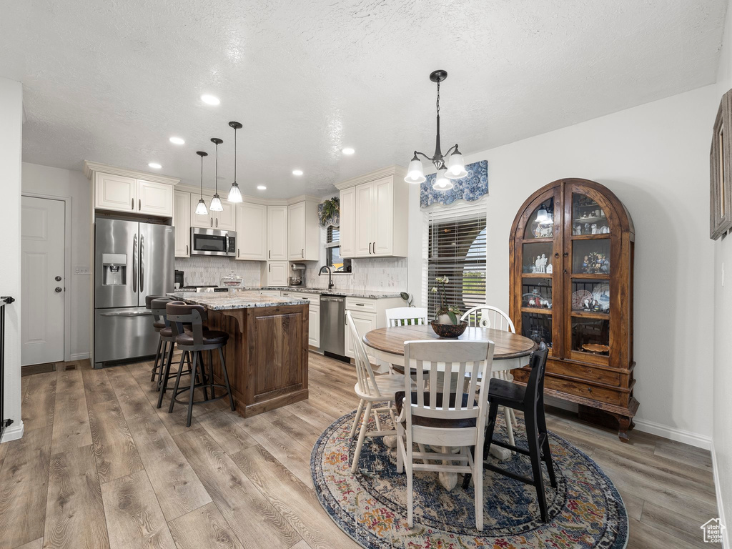 Dining area featuring light hardwood / wood-style floors, sink, and an inviting chandelier