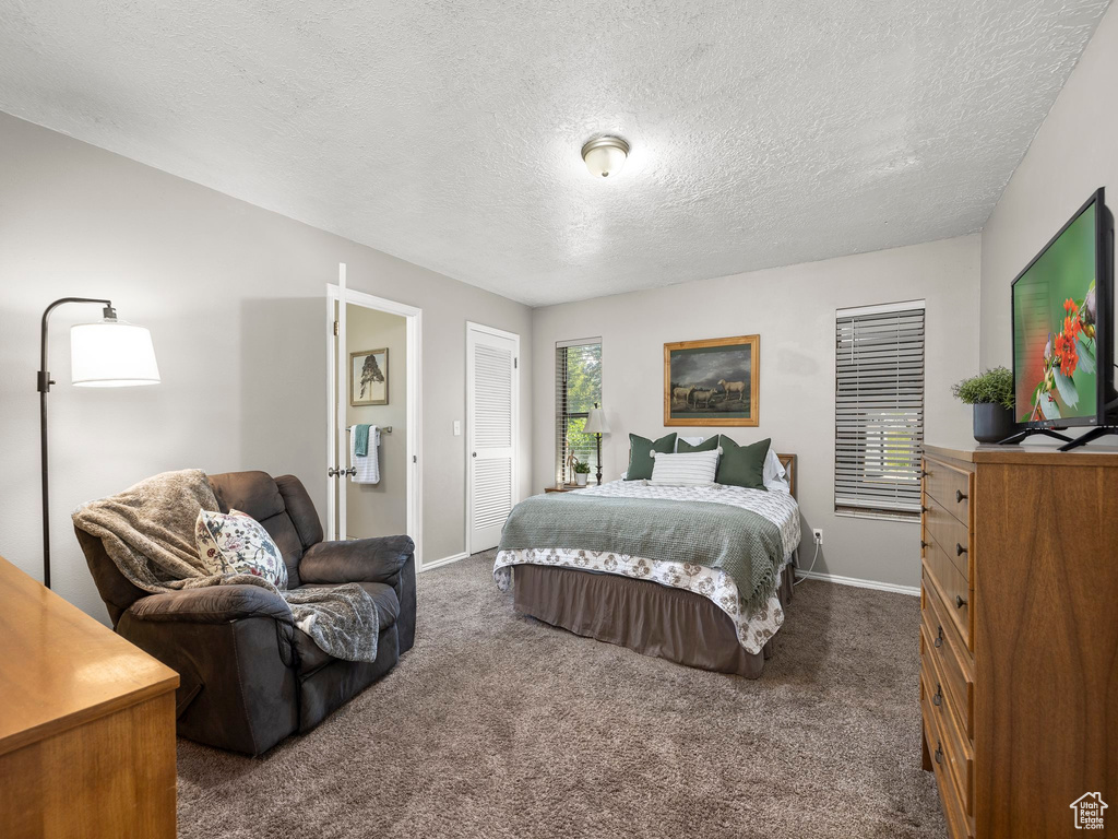 Bedroom with dark colored carpet, a closet, and a textured ceiling