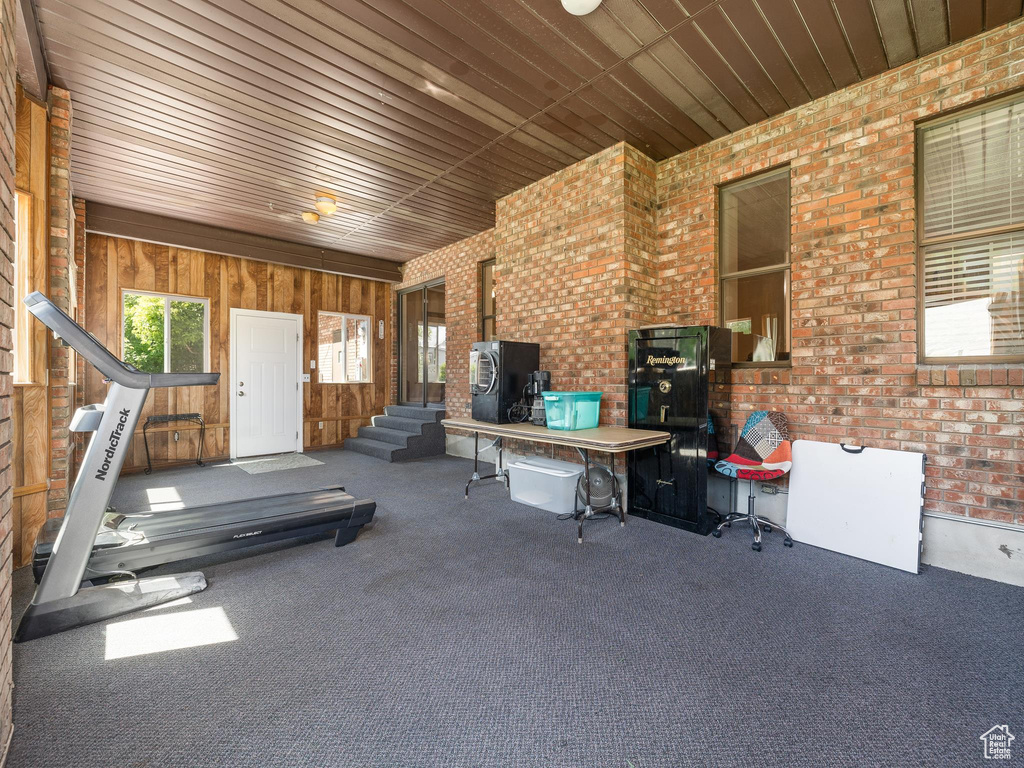 Workout room with brick wall, wood ceiling, a wood stove, and wood walls