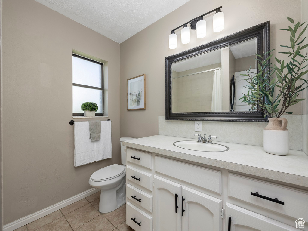 Bathroom with tile floors, a textured ceiling, oversized vanity, and toilet