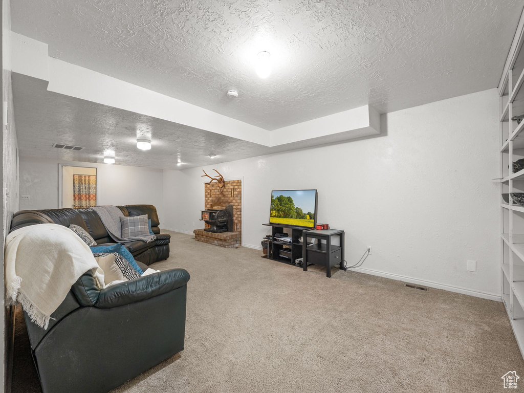 Living room featuring brick wall, carpet, a textured ceiling, and a fireplace