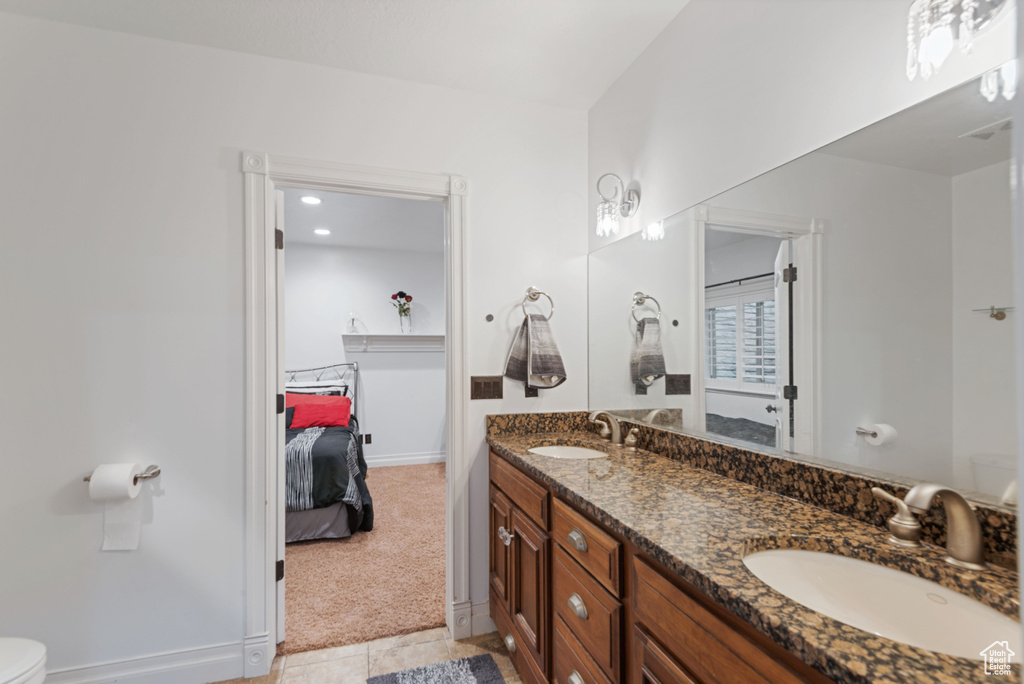 Bathroom featuring dual sinks, tile flooring, toilet, and large vanity