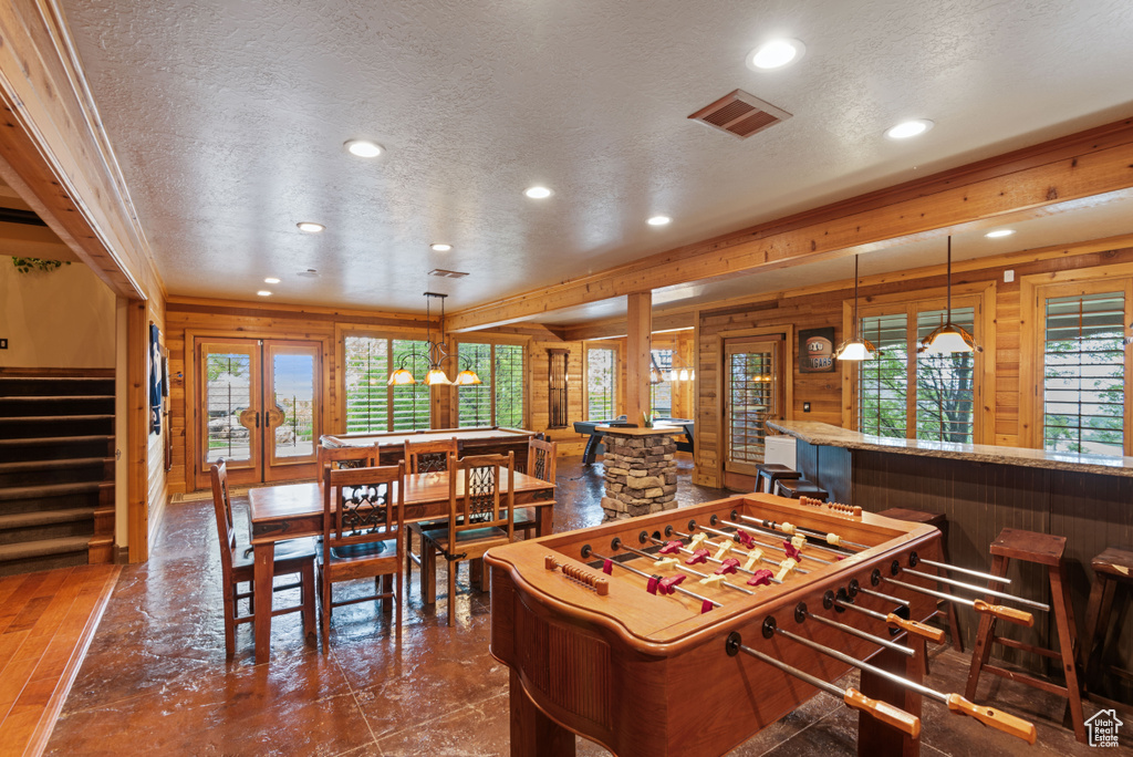 Game room with a chandelier, wooden walls, plenty of natural light, and a textured ceiling