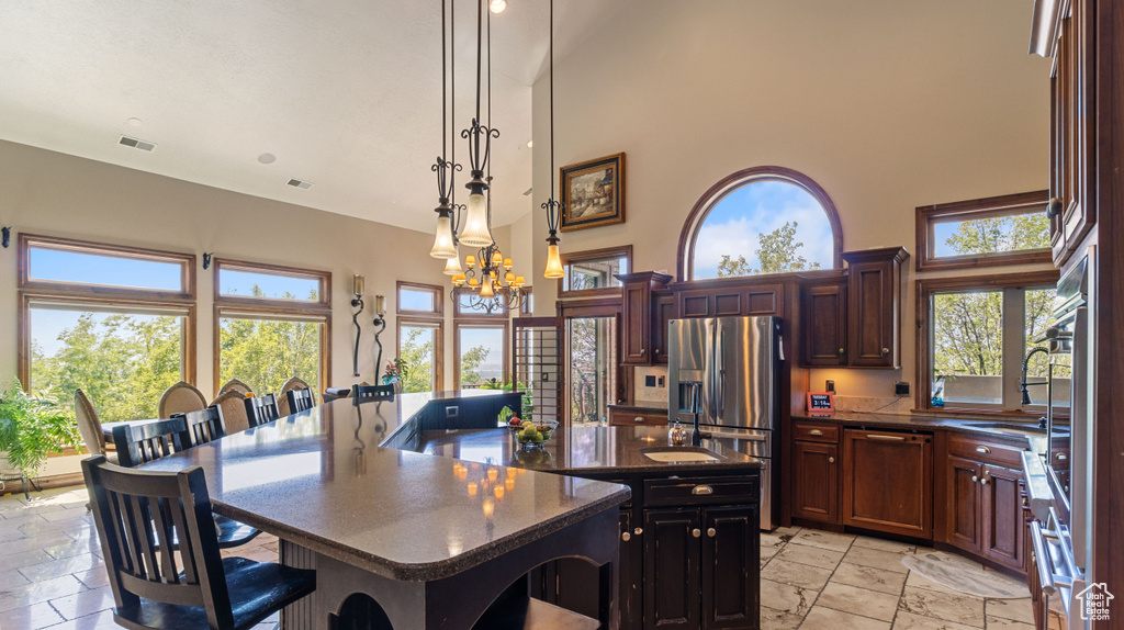 Dining room with light tile patterned floors, sink, a high ceiling, and an inviting chandelier