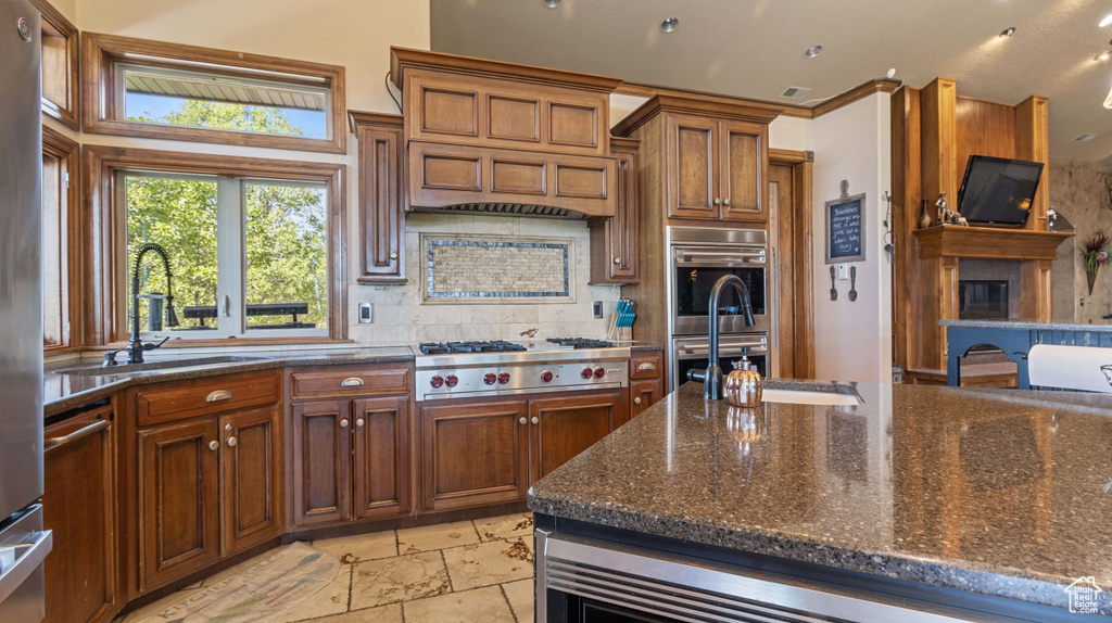 Kitchen with stainless steel appliances, custom range hood, light tile patterned floors, tasteful backsplash, and sink