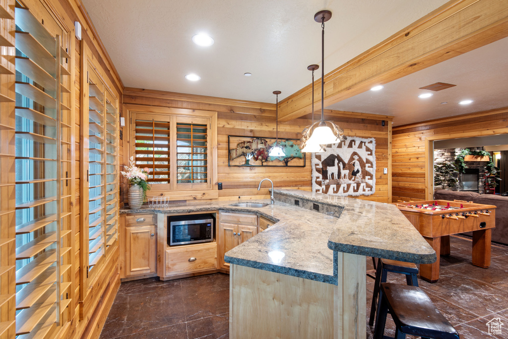 Kitchen with wood walls, stainless steel microwave, and dark tile flooring