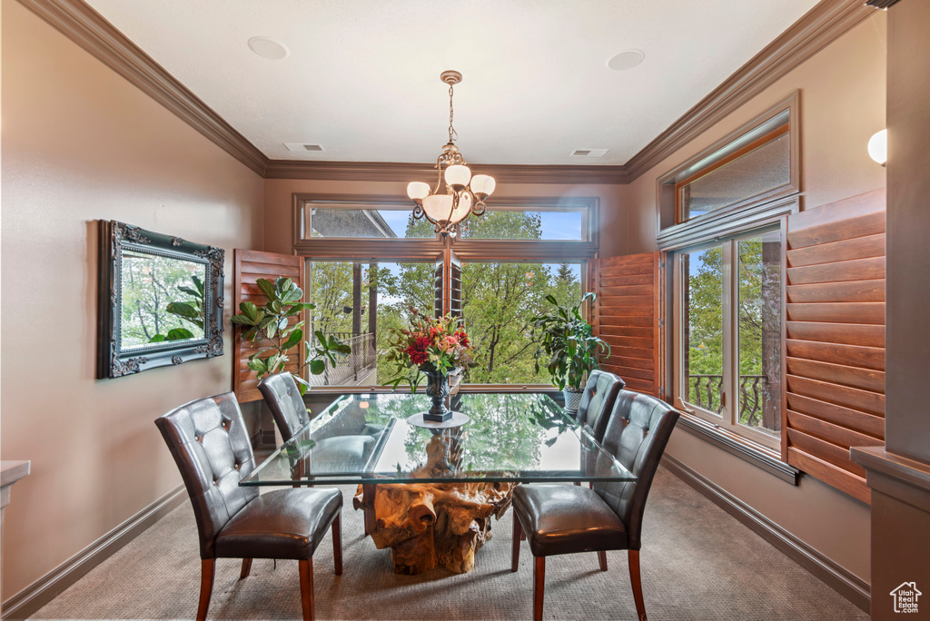 Dining space with an inviting chandelier, carpet floors, and crown molding