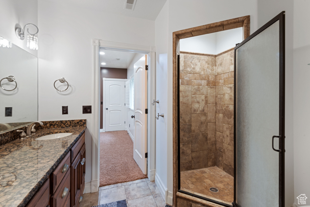 Bathroom featuring a shower with door, tile flooring, and vanity