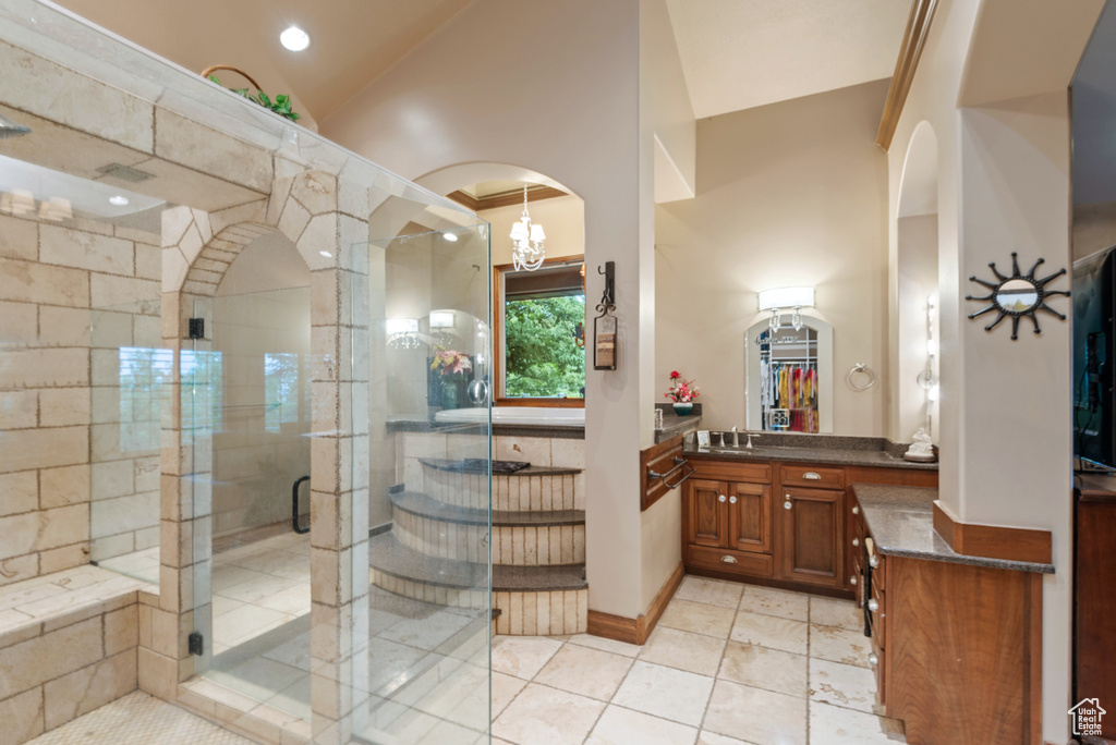 Bathroom featuring a notable chandelier, tile flooring, a shower with door, high vaulted ceiling, and vanity