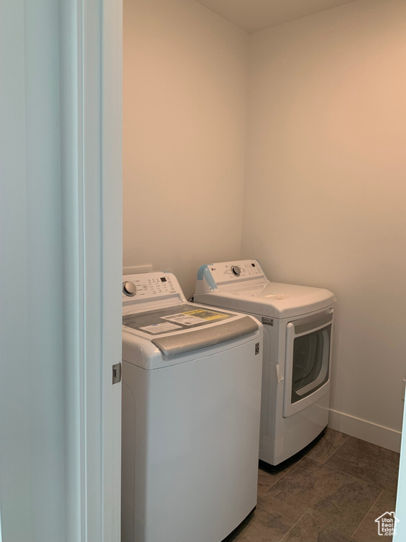 Clothes washing area with dark tile flooring and independent washer and dryer