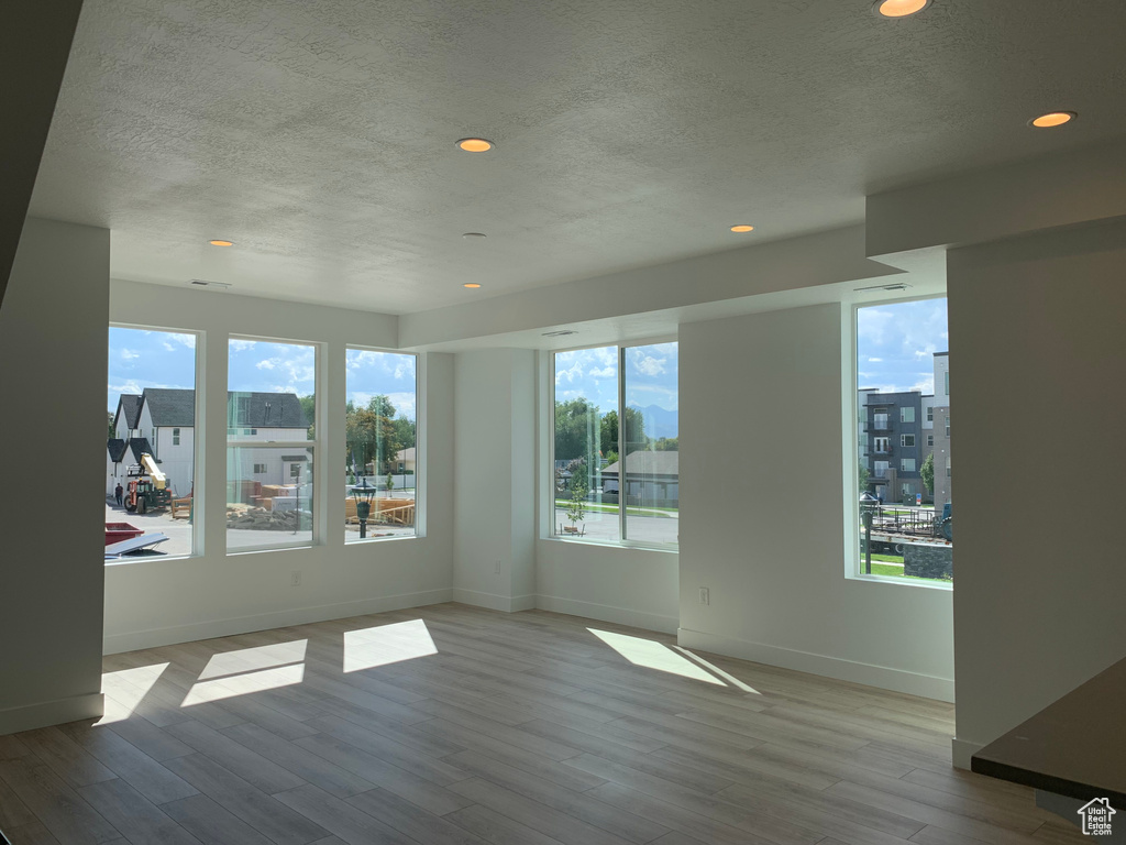 Unfurnished room featuring a textured ceiling, a wealth of natural light, and wood-type flooring