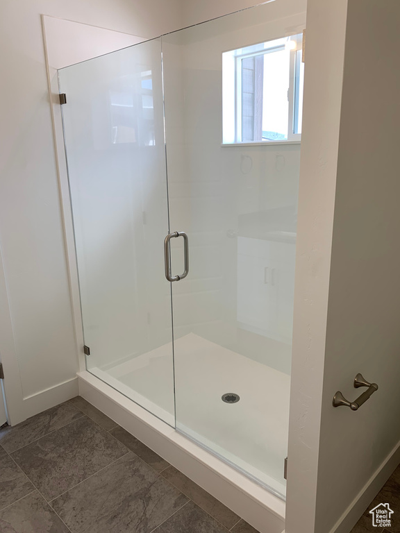 Bathroom with tile flooring and a shower with door