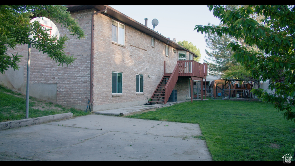 Rear view of house featuring a wooden deck and a yard