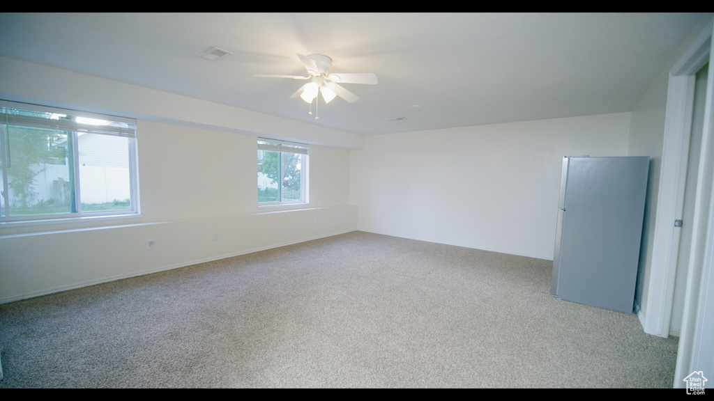 Carpeted spare room featuring ceiling fan