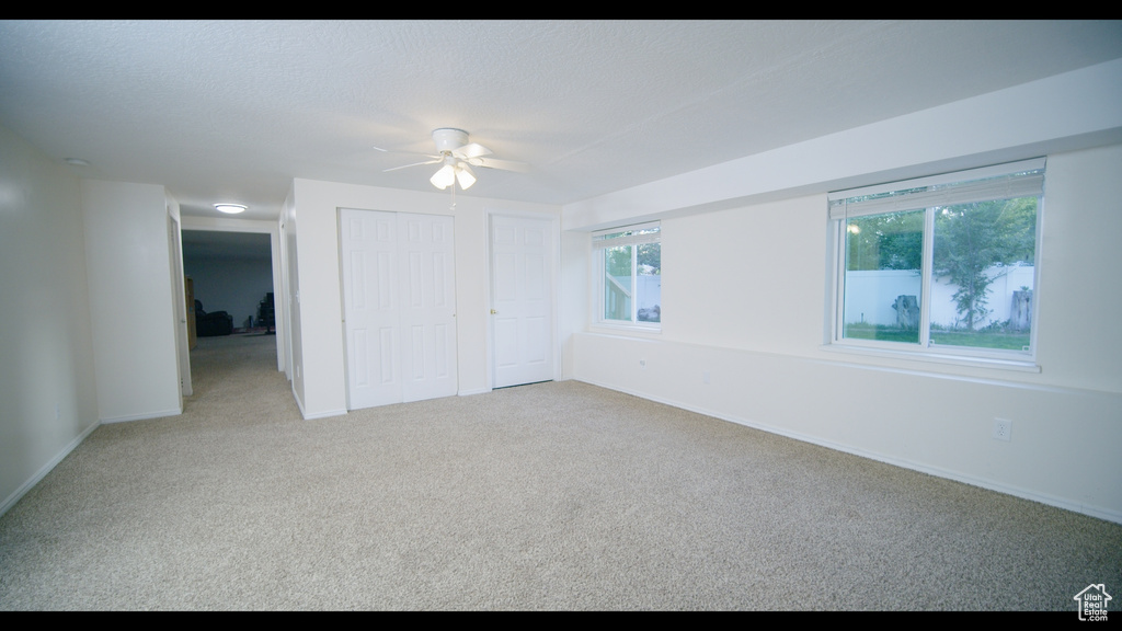 Unfurnished bedroom featuring carpet floors, multiple windows, and ceiling fan