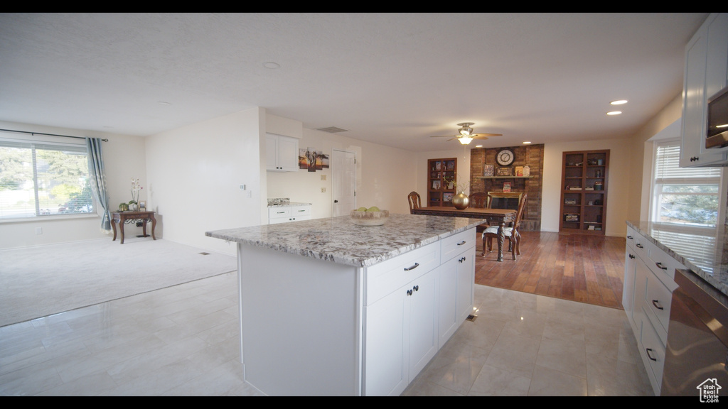 Kitchen featuring ceiling fan, dishwashing machine, light tile flooring, a kitchen island, and white cabinets