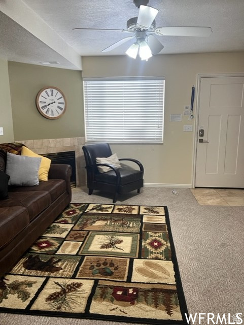 Carpeted living room with ceiling fan and a textured ceiling