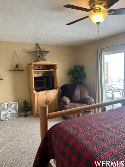 Bedroom featuring ceiling fan, a textured ceiling, and light colored carpet