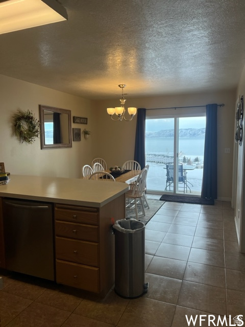 Kitchen with dishwasher, plenty of natural light, dark tile floors, and a chandelier