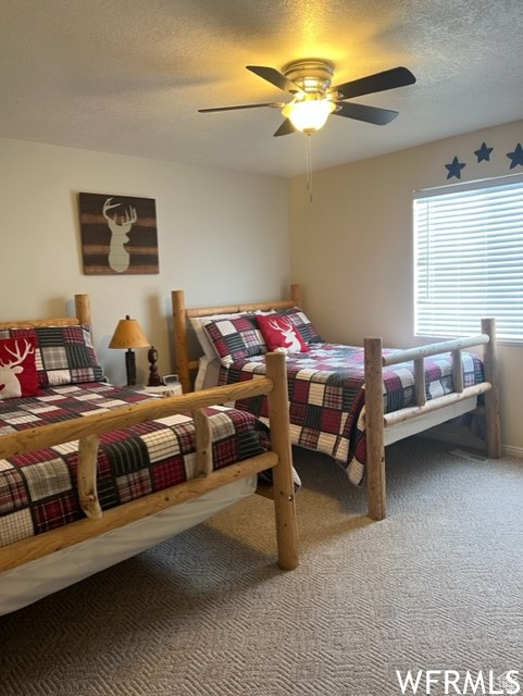 Carpeted bedroom featuring ceiling fan and a textured ceiling