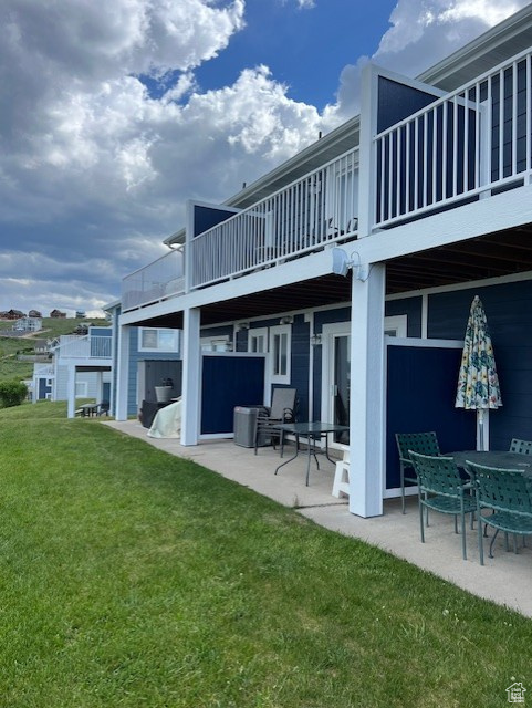 Rear view of property featuring a patio, a balcony, and a yard